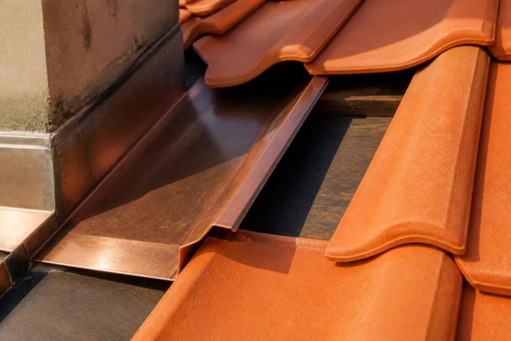 Miedziane elementy dachowe i pomarańczowe dachówki ceramiczne na dachu