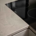 Czarna płyta indukcyjna z okrągłymi polami grzewczymi na jasnym blacie kuchennym